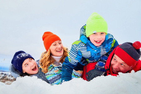 Portrait of a family with four people having fun in the snow. Dad, mom and two sons in winter day outdoorの写真素材