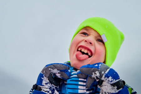 Cute boy dressed in coat have fun on a winter walk in snow