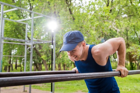 Attractive fitness man doing exercises in a summer park