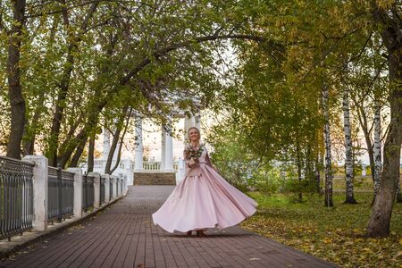 Woman in pink dress in an autumn park. Happy bride with nice bouquet in wedding dayのeditorial素材