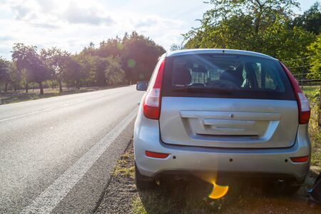 Car on the road and landscape with field and sky in an summer on an autumn dayの写真素材