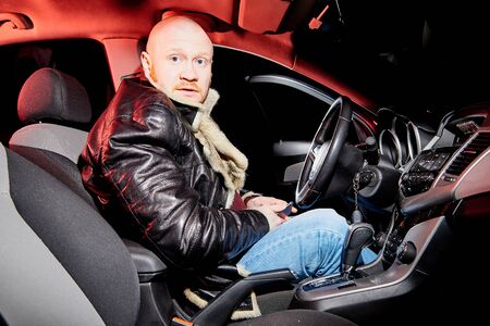 Male driver in a leather jacket smoking in the car in the dark time. Drunk driver in the car. Night...