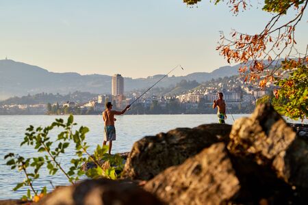 Geneva, Switzerland - September 20, 2018: Silhouettes of fishermen on the lake at sunset in a summer eveningのeditorial素材