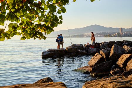 Geneva, Switzerland - September 20, 2018: Tourists on the beach of lake at sunset in a summer...