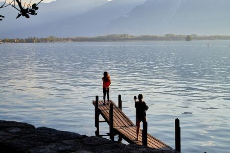 Geneva, Switzerland - September 20, 2018: Tourists on the beach of lake at sunset in a summer eveningのeditorial素材