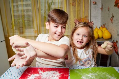 Children brother and sister having fun with flour and dough at homein the kitchen. Cooking, fun and mischiefの写真素材
