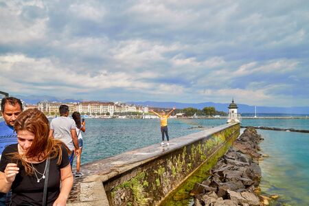 Geneva, Switzeland - September 21, 2018: Geneva, Switzeland - September 21, 2018: Tourisths on embankment near famous fountain on lake Geneva in a nice day with blue sky and clouds in summerのeditorial素材