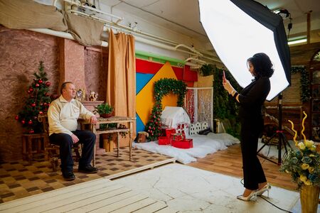 Kirov, Russia - January 24, 2019: Young woman shoots an elderly man in a photo Studio with large...