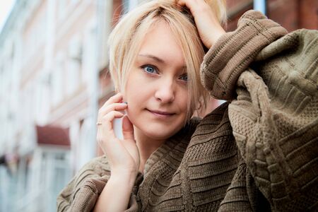 Blonde girl near near the facade of a large red brick building with windows in the Central part of the ancient city. Walk in downtown. Portrait of a funny pretty girl on the street of the townの写真素材