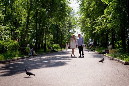 Kirov, Russia - June 09, 2019: Young man and woman couple walk in the park and hold hands each other. Spring or summer love story. Young happy familyのeditorial素材