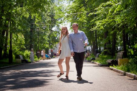Kirov, Russia - June 09, 2019: Young man and woman couple walk in the park and hold hands each other. Spring or summer love story. Young happy familyのeditorial素材