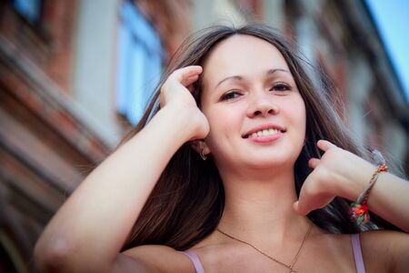Brunette girl near red brick facade of old building in the central part of city in a summer day....