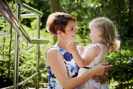 Happy mother and daughter in the park. Family resting and hugging outdoor. Beauty nature scene with...