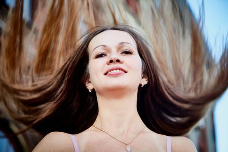 Portrait of brunette girl with flying hair in the central part of the old city in a sunny summer or...