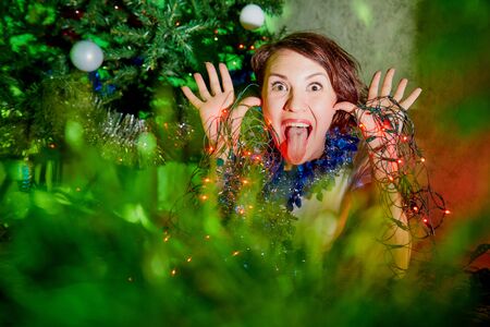 Nice young woman near Christmas tree in the room. Family selebration at homeの写真素材