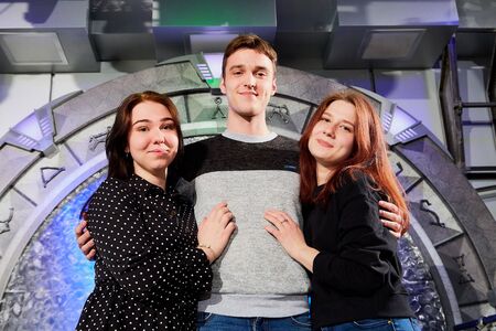 Kirov, Russia - April 18, 2019: Guy and two girls posing on a small stage in a dark hall with...