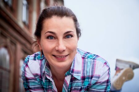 Brunette girl near near the facade of a large red brick building with windows in the Central part of the ancient city. Walk in downtown. Portrait of a funny pretty girl on the street of the townの写真素材