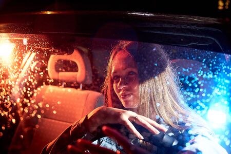 Beautiful young woman in the car at night