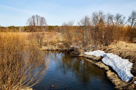 Small river in a nice sunny day in early spring. Russian nature landscape with water, trees and blue skyのeditorial素材