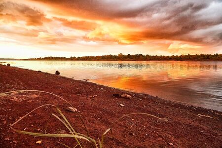 Sky with fantastic, amazing, stormy, disturbing red clouds over the river on a summer or autumn...