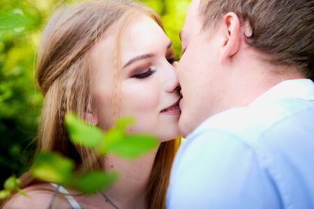 Young man and woman couple walk in the park and kiss each other. Spring or summer love story. Young happy familyの写真素材