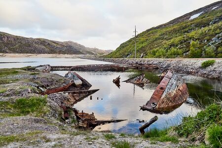 Graveyard of old ships in Teriberka in Russia. Destroyed ships in the water in a summer, spring or...