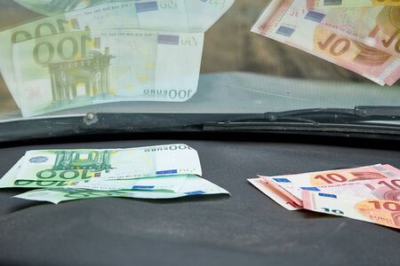 Euro banknotes on the black dashboard and their reflection in the windshield inside of a carの写真素材
