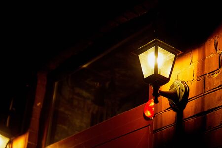 Retro lantern on the stone wall and illuminates street on a dark night in the old town and black...