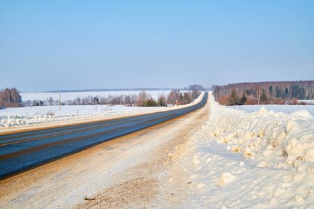 Winter landscape with country road in snowy field in sunny day in Russiaの写真素材