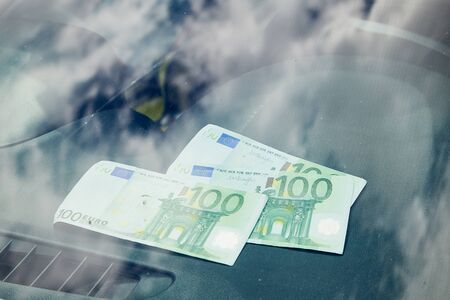 Euro banknotes on the black dashboard and their reflection in the windshield inside of a carの写真素材