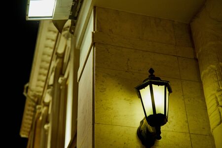 Retro lantern on the stone wall and illuminates street on a dark night in the old town and black backgroundの写真素材