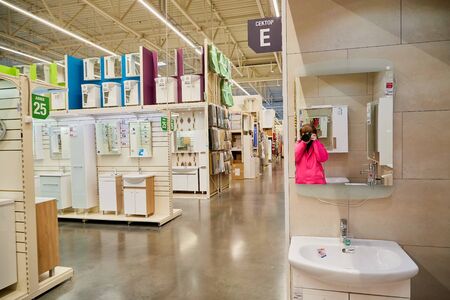 Kirov, Russia - November 23, 2019: Trading hall with goods and reflection in mirror of a girl taking picture in it in the store Leroy Merlin. Building materials and things for the house in big shopのeditorial素材