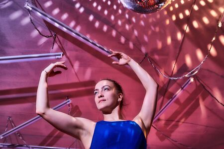 Flexible gymnast girl standing in hall or on stage with interesting light. Portrait of young woman in sport dress. Performance and posing dancing model. Sport, training, active lifestyle concepの写真素材