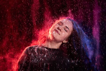 Plump teen girl during a photo shoot with flour with colored backlight and dark background. Teenage...