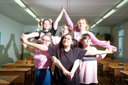 Kirov, Russia - September 28, 2019: Group of female students or schoolchildren with bow on hair in classroom. Teenagers having fun and posing together in the school and doing pentacleのeditorial素材