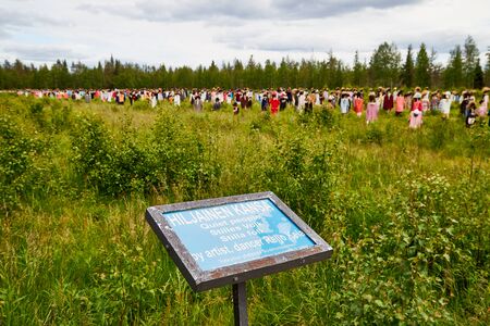 SUOMUSSALMI, FINLAND - JULY 24, 2019: A sign near field with group of objects in people clothes which looks like crowd in field in a summer of autumn. Finland. Installation Reijo Kela Silent Peopleのeditorial素材