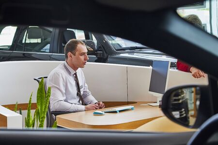 Murmansk, Russia - June 21, 2019: Manager in showroom with cars of dealership Toyota in Murmansk...