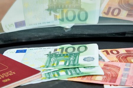 Euro banknotes and red passport on the black dashboard and their reflection in the windshield inside...