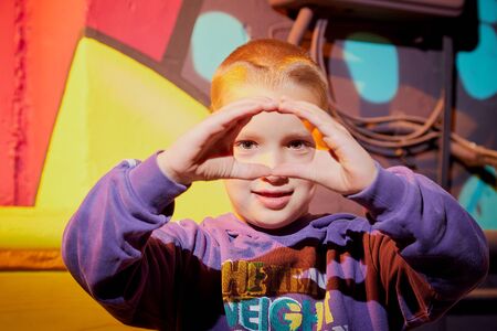 Kirov, Russia - August 11, 2019: Funny boy in itresting museum named Fantazarium full of drawing and graffiti. Teenager indoors with pictures on the wallのeditorial素材