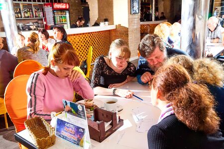 Kirov, Russia - September 17, 2019: People at table in small cafe or restaurant during intellectual game. Hungry group discussing the menu in the restaurant and waiting for the waiter to get foodのeditorial素材