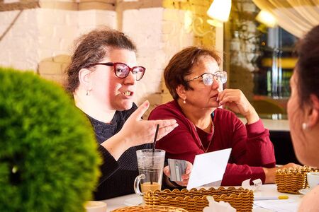 Kirov, Russia - September 17, 2019: People at table in small cafe or restaurant during intellectual game. Hungry group discussing the menu in the restaurant and waiting for the waiter to get foodのeditorial素材