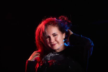 Portrait of chubby teen girl illuminated by red light and black background. Model in a photo shoot...
