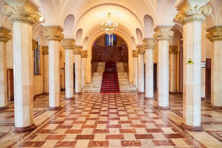 Large hall with white columns and a square checkered red tile pattern on the floor. Background for photoshoot indoorsの写真素材