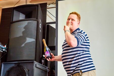 Kirov, Russia - September 19, 2019: Happy man with bottle posing for a photo shoot. Winner indoors
