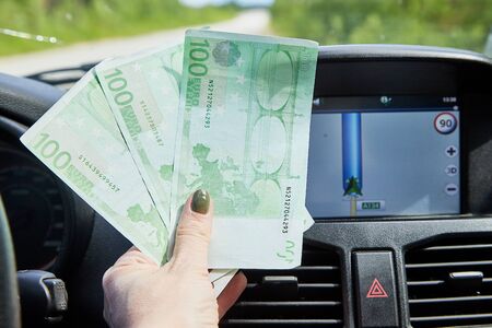 Helsinki, Finland - June 25, 2019: Euro banknotes of various denominations in a woman hand inside of a car and road with nature outsideの写真素材