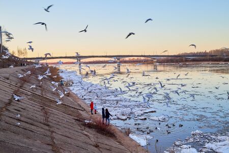 Kirov, Russia - April 13, 2019: Ice drift on the river and people watching it from the shore in the evening at sunset in the Northern part of Russiaのeditorial素材