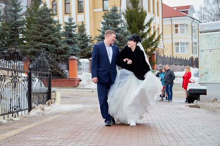 Kirov, Russia - March 22, 2019: Bride and groom walking with group of young friends on the street of city on a cold winter or autumn day in Russiaのeditorial素材