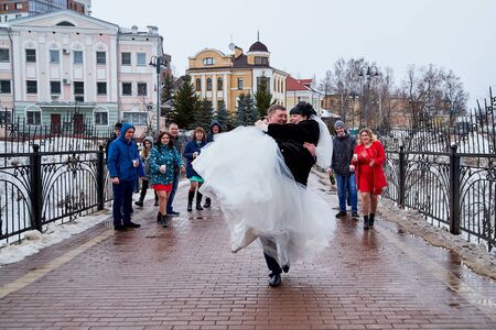 Kirov, Russia - March 22, 2019: Bride and groom walking with group of young friends on the street of city on a cold winter or autumn day in Russiaのeditorial素材
