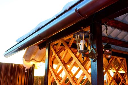Streetlight on yellow wooden gazebo on a Sunny winter day with blue sky. Lattern and wooden plank