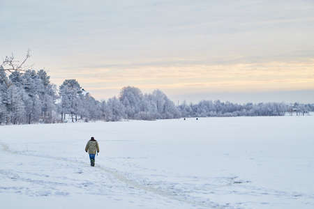 Kirov, Russia - December 15, 2018: Fisherman on the ice of the river on a winter day, morning or evening. View of the river or lake under the snow with a fisherman in a warm dressのeditorial素材